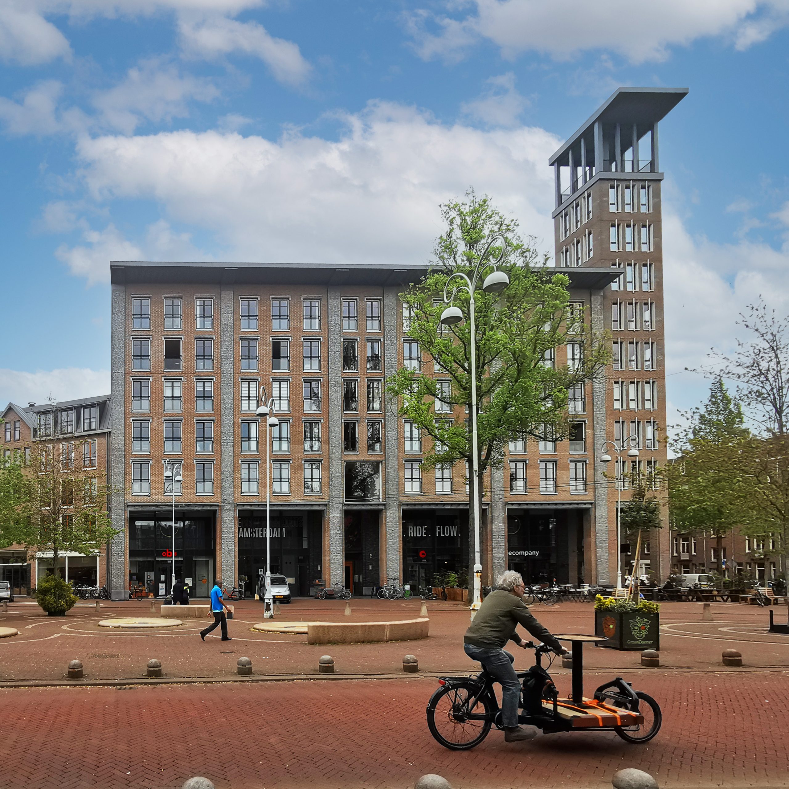 Modern gebouw met fietsen en wandelaar in Amsterdam.