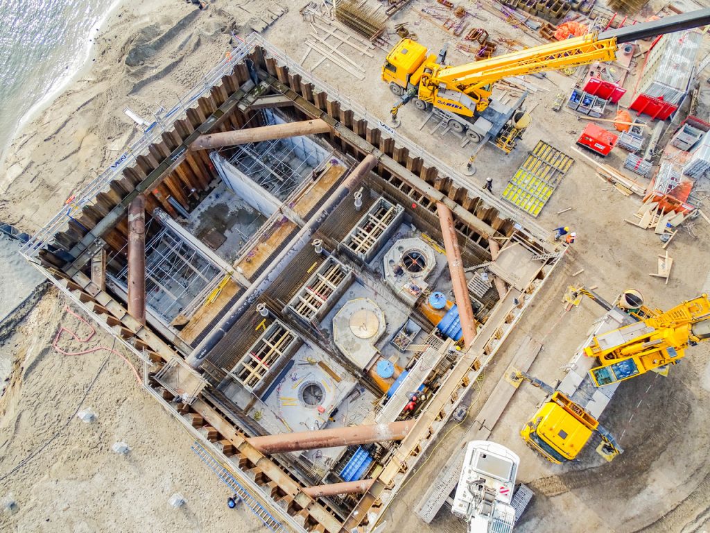Constructieplaats aan zee met kranen van bovenaf gezien.