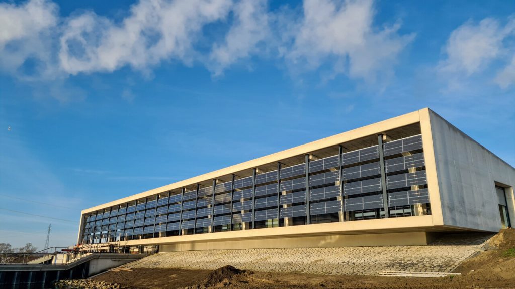 Moderne gebouw met zonnepanelen tegen blauwe lucht.