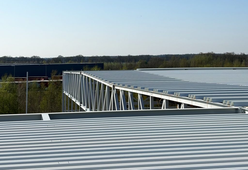 Staalconstructie van een industrieel gebouw tegen blauwe lucht.